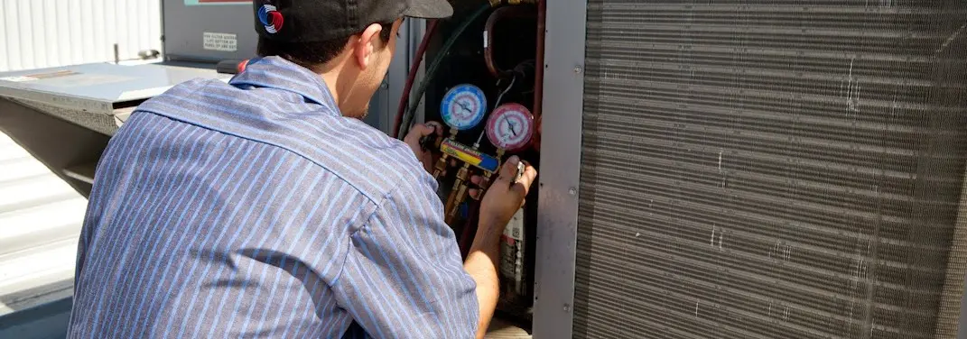 HVAC technician servicing a condenser unit in Ringwood